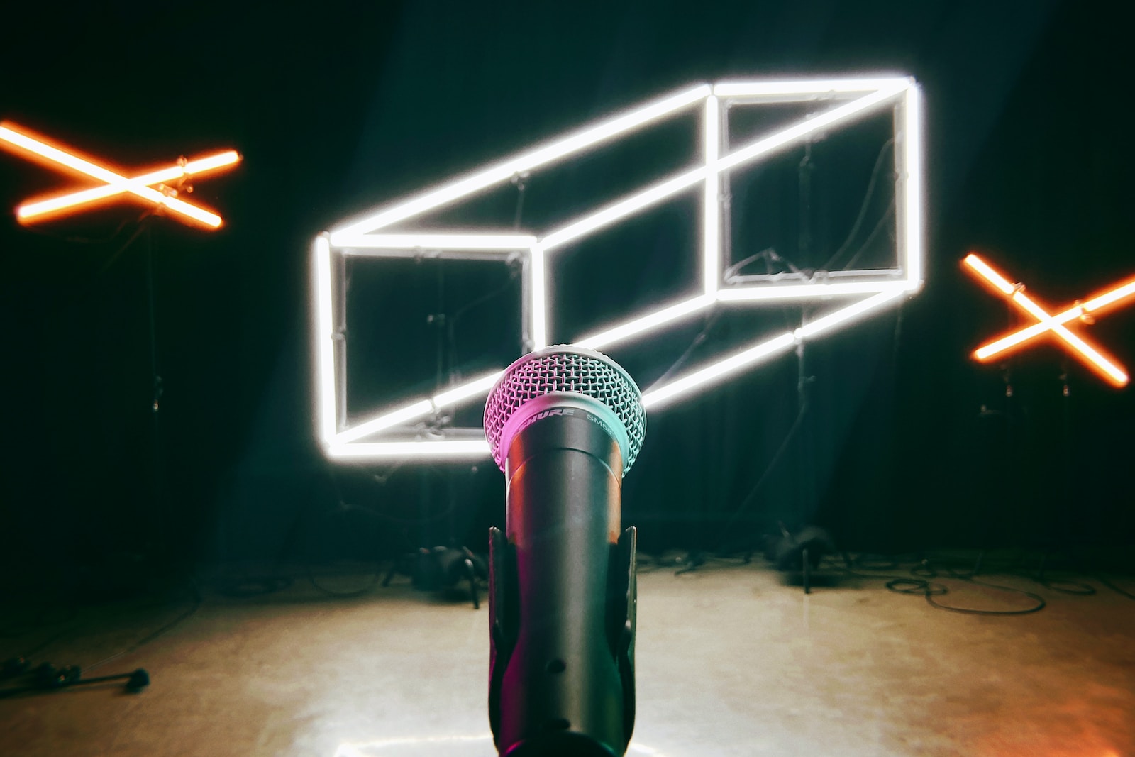 Illustrative photo of microphone in front of abstract neon lights